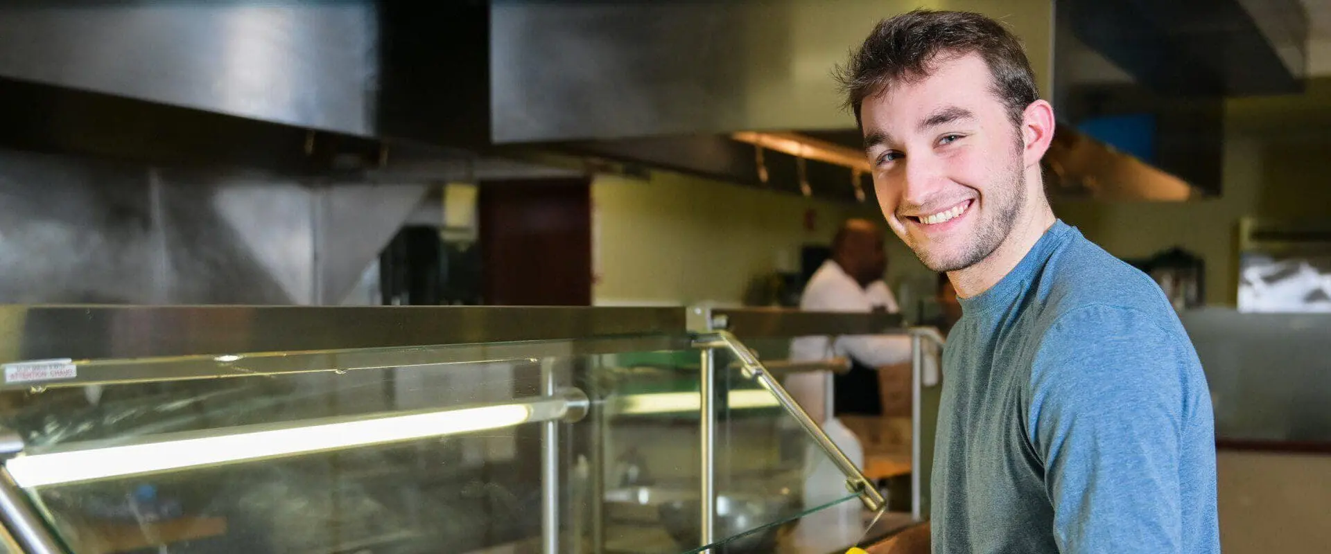 Student smiling and grabbing pizza from line
