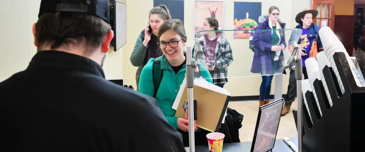 Students waiting in line with cashier in foreground