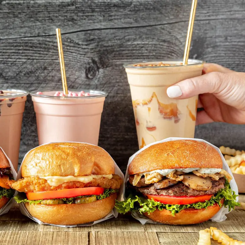 Burgers on a wood table with milkshakes in the background